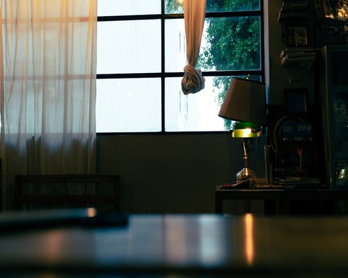 A well lit reading space near a window with sheer curtains